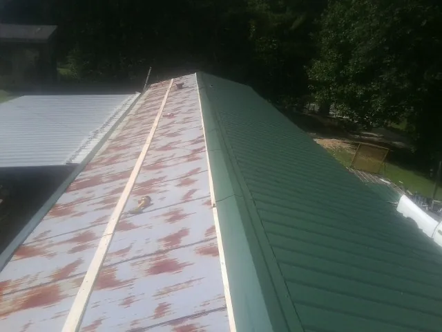 Old rusted panels beside newly installed green metal roofing — Wind Damage Roof Repair by Roofing Brothers in Jones Mills