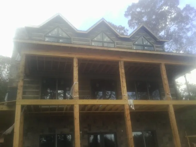 Dormers and porch framing on a large log home under construction — Roof Coating work by our crew in Jones Mills