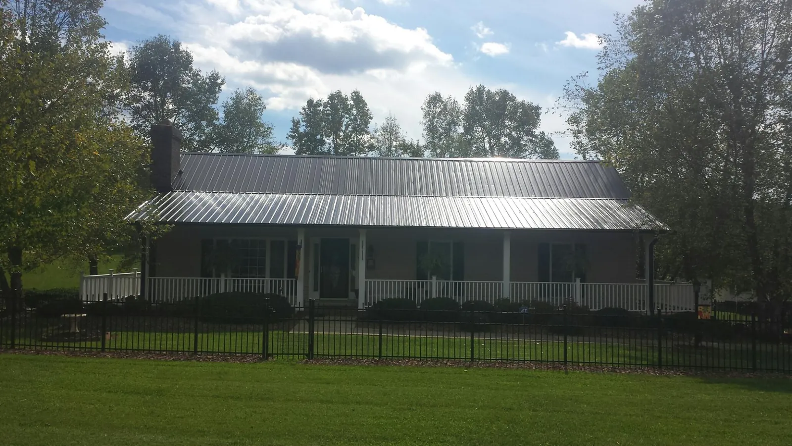 Gray metal roof on a brick ranch with a full width front porch — Gutter Guard Installation work by our crew in Jones Mills