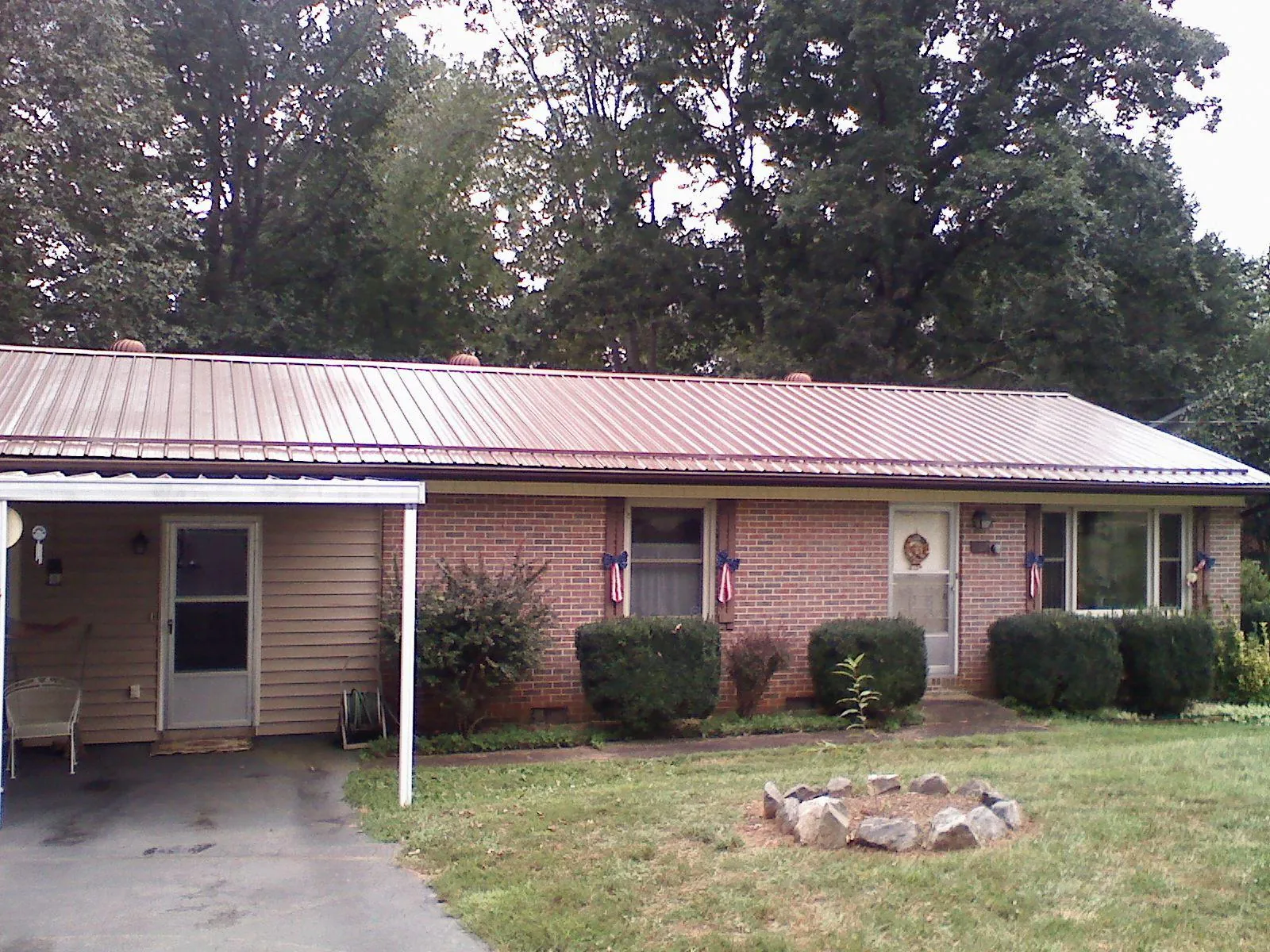 Bronze metal roof and carport on a brick ranch home — Roof Repair work by our crew in Jones Mills