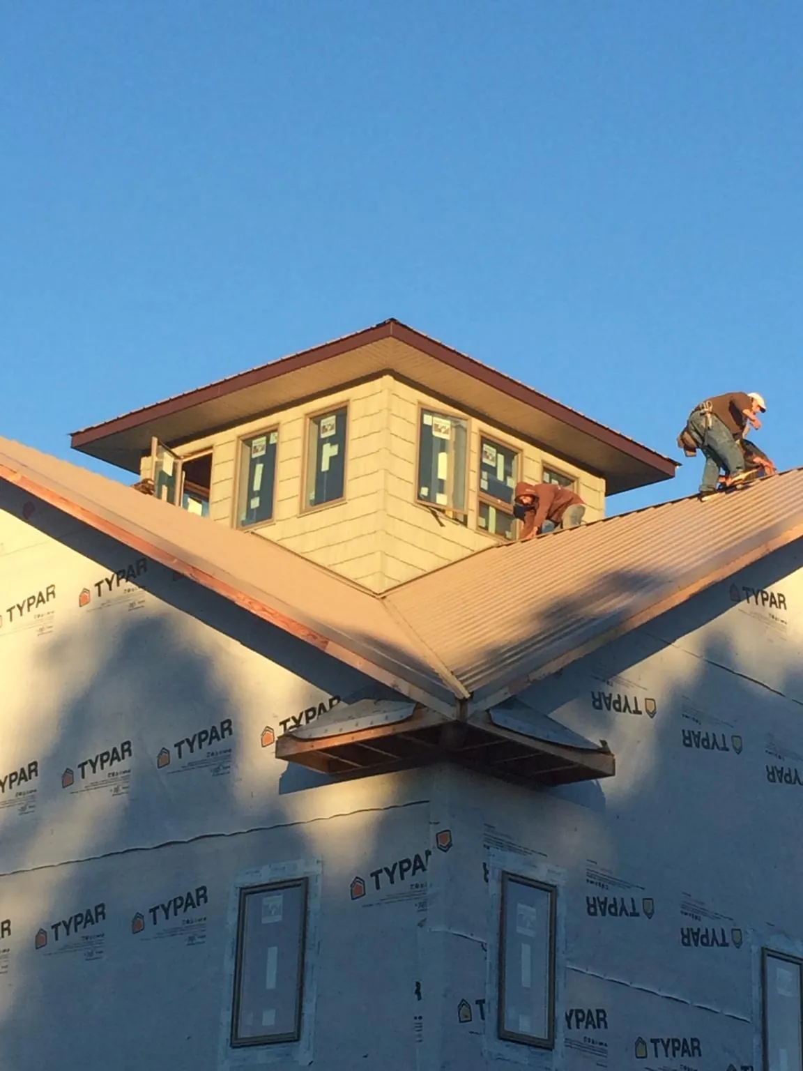 Roofers working around a rooftop cupola on a new metal roof at sunset — Roof Waterproofing in Jones Mills by Roofing Brothers